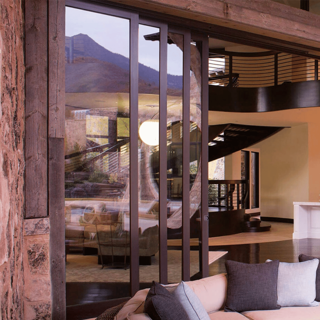 opened lift and slide patio doors with a view into a very modern and brown home