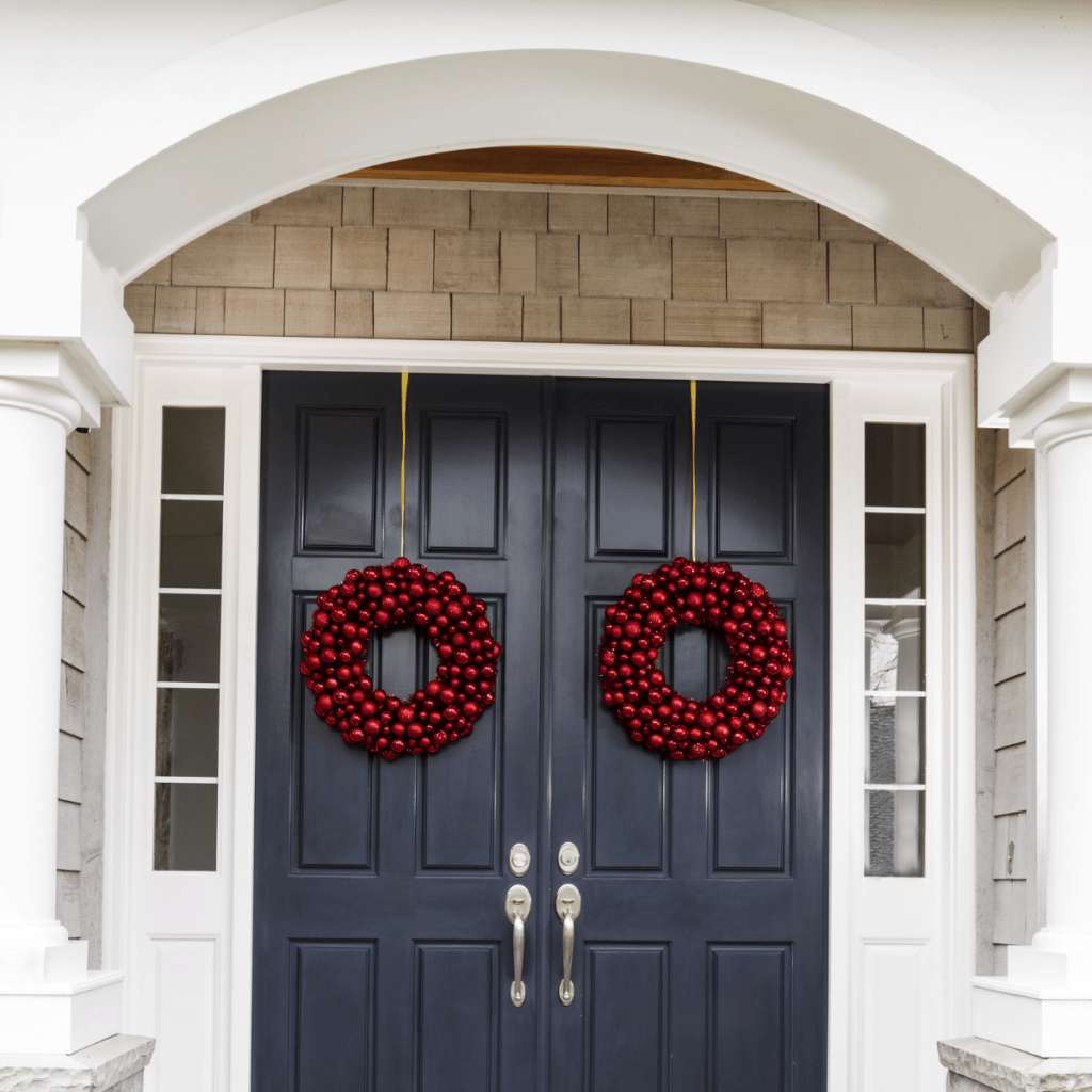 entry doors with red wreaths on them and small viewing windows on the side