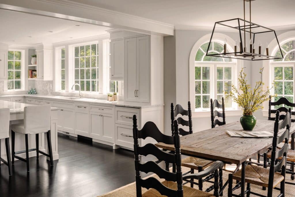 round top windows in the dining room of an all white modern kitchen and dining area with black dining chairs