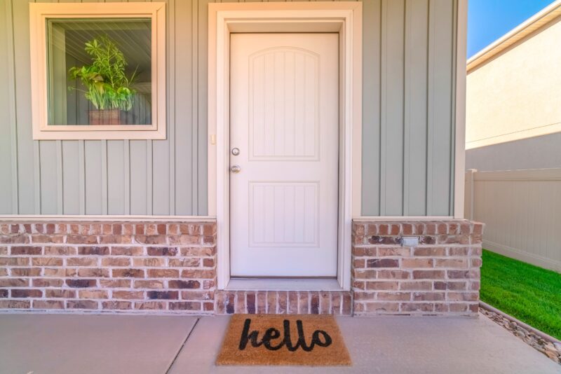 white front door of home with a welcome mat below it on the porch