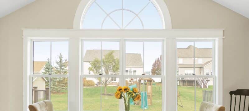 a panel of windows in a dining room that look out into a backyard with more houses in the background