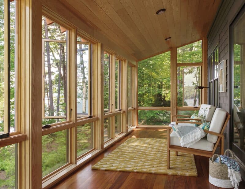 cozy outdoor patio with windows looking out into a wooded area